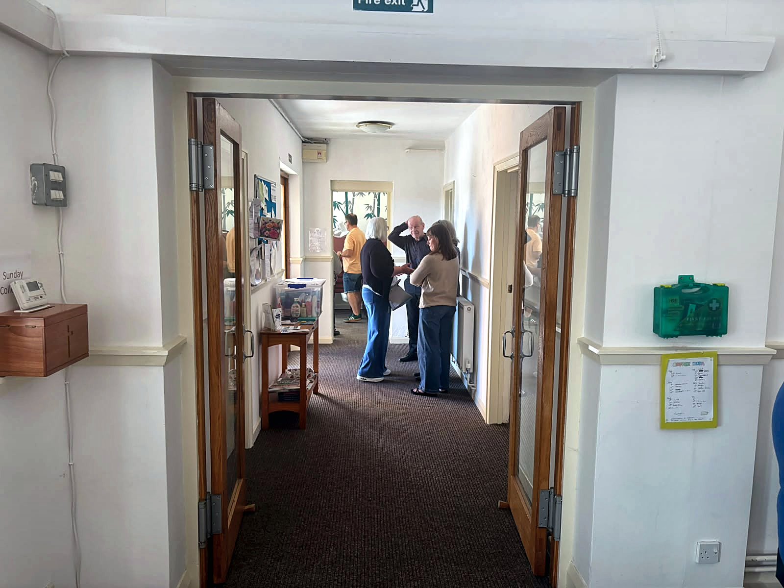 People chatting and welcoming one another in the church hallway